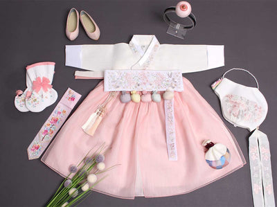 Beauty baby girl hanbok in white and light pink. The accessories are color matched that makes this hanbok look very pretty and is sure to get compliments for the baby who wears this.