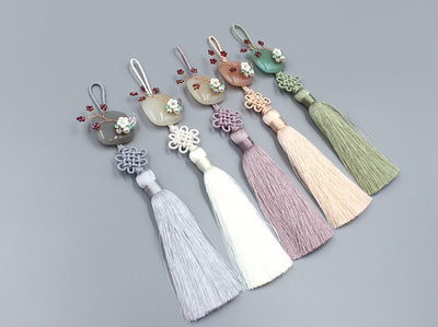 Dress up your look and feel unique with the Floral Gem Tassel Norigae. It comes in either gray, cream, magenta, orange, or leafy green.