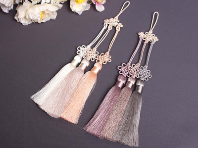 The x Chrysanthemum Tassel Norigae is a decorative tassel that will bring the wearer luck and wealth. The two color options include ivory, maroon, and peach or gray, magenta, and light purple.